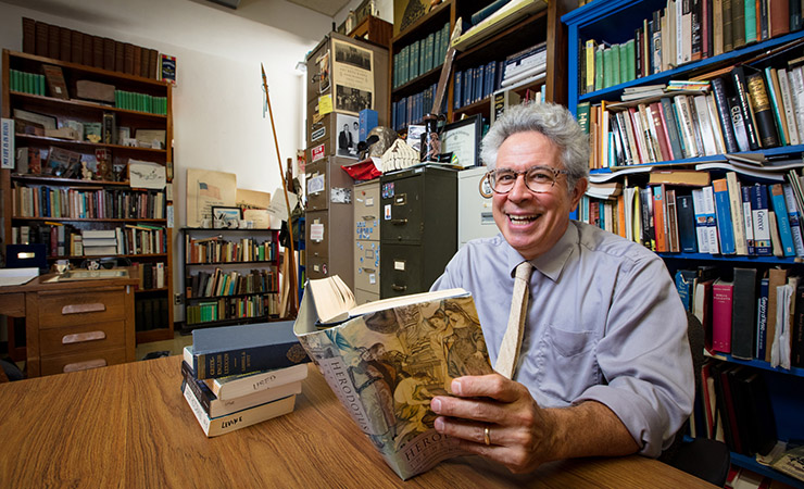 man reads Herodotus in cluttered office