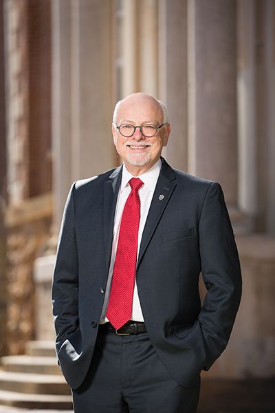 man in red tie standing before columns