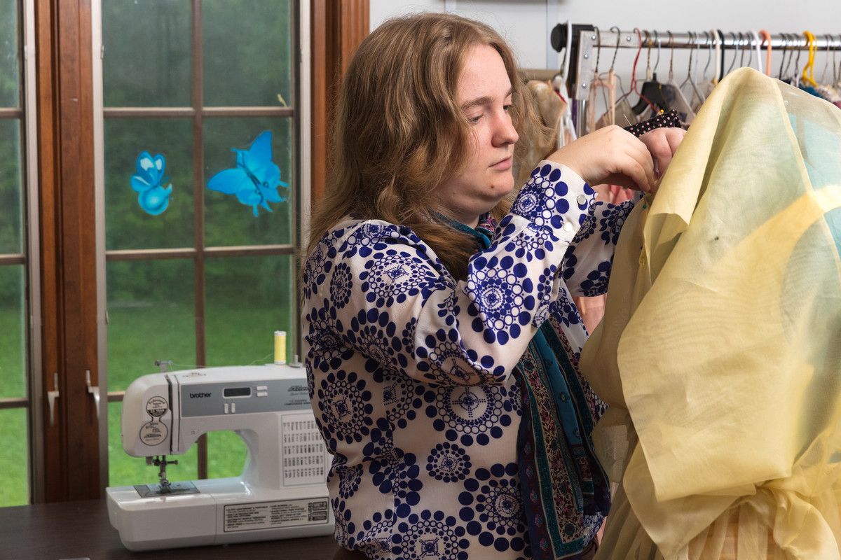 student sews fabric on mannequin