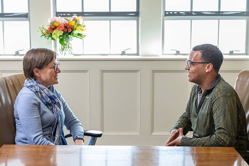 Woman staffmember visits with male student.