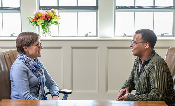 Female staffmember visits with male student.