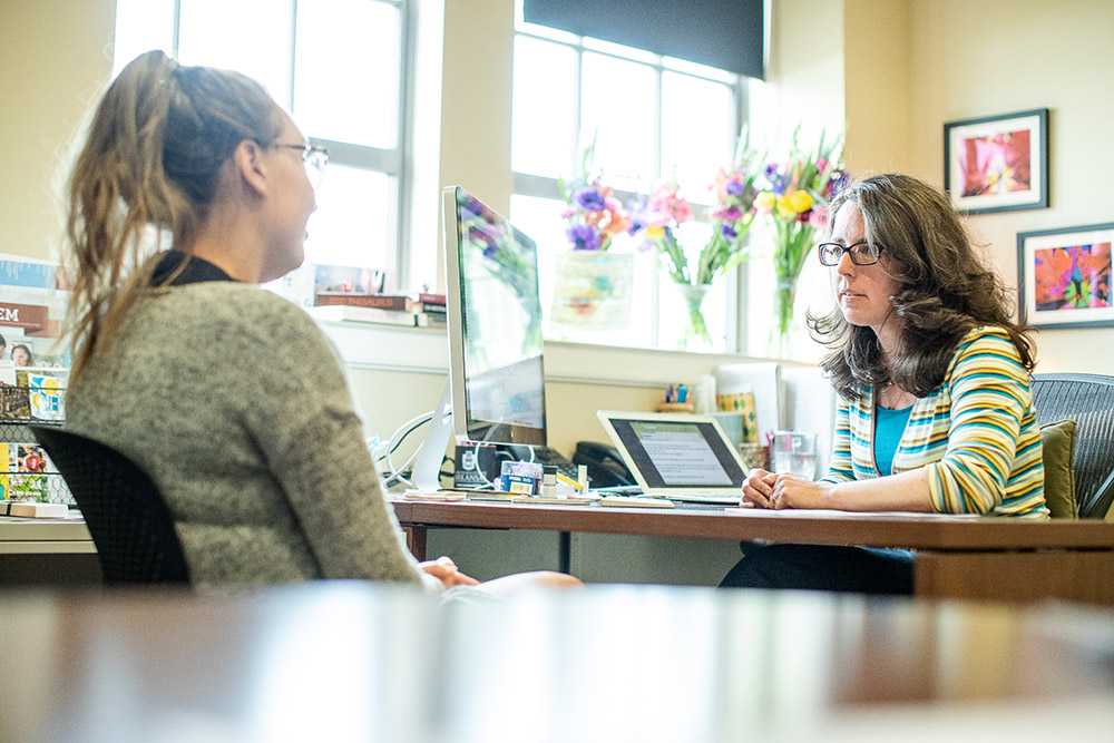 woman conversing with female student in office