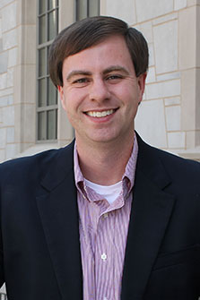 man smiles at camera in front of Gearhart Hall