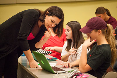 Woman looks at student's laptop