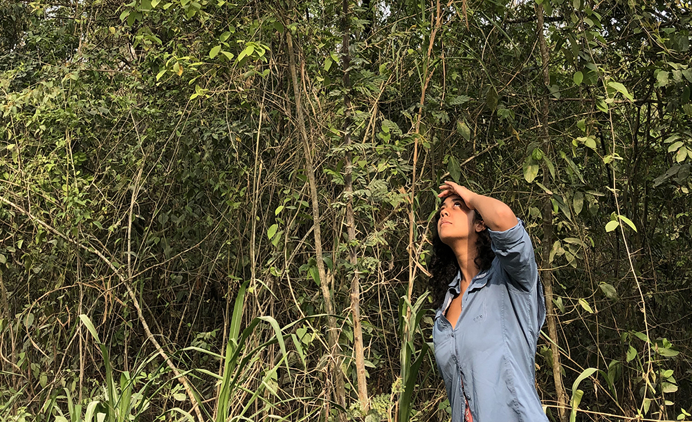 Female student shields eyes from sun in jungle
