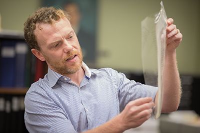 Man pulls manuscript folio from protective cover