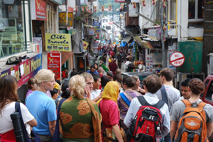 A group of students, shown from behind, view a busy street in India.