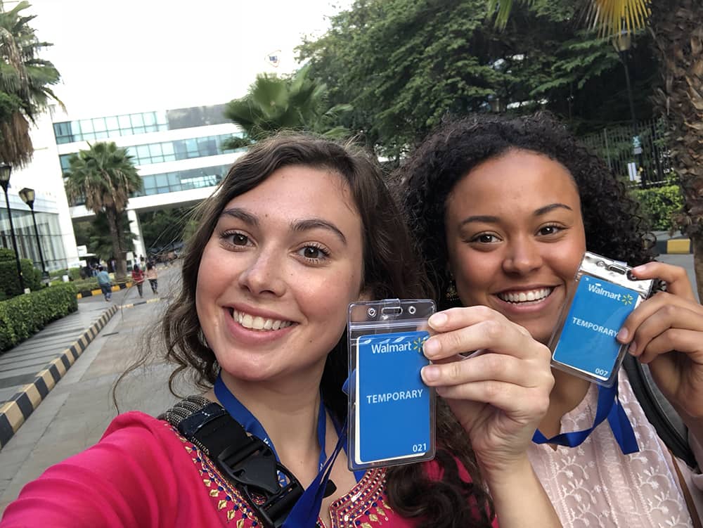 Students in a palm-tree lined parking lot hold up Walmart Intern badges.