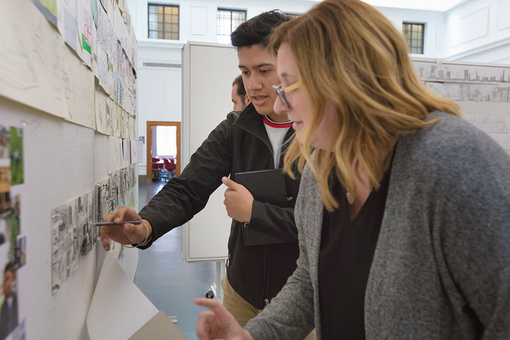 Architecture student and professor examine sketches.