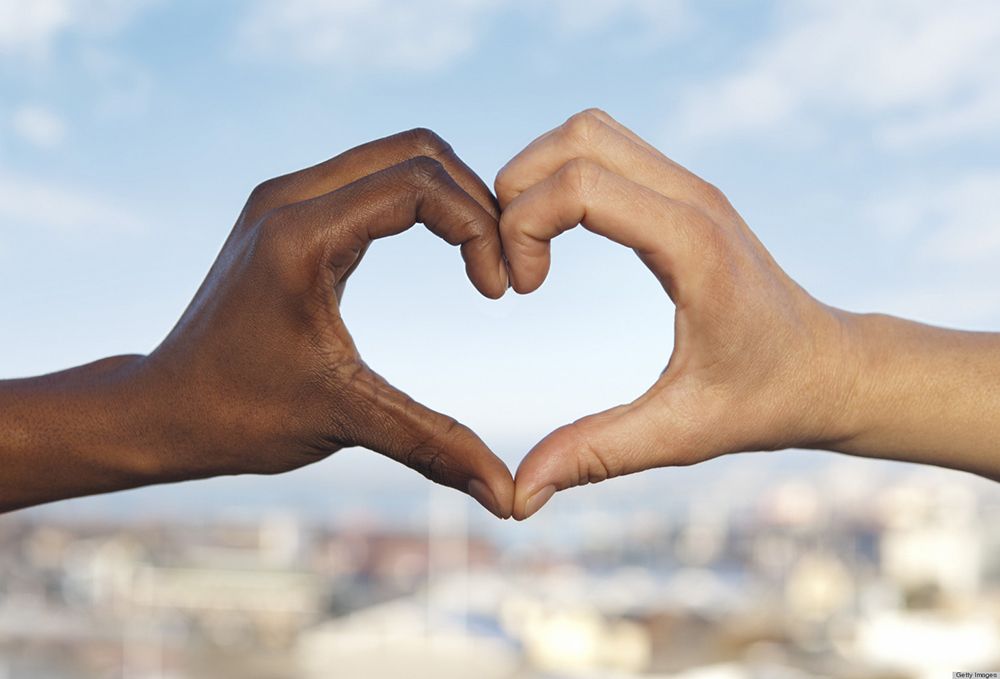 Two hands, of different races, form a heart.