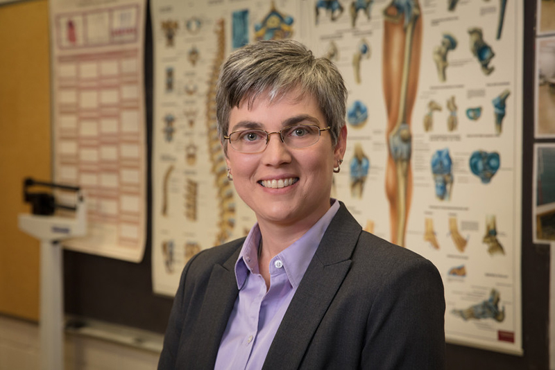 woman stands in front of kinesiology poster